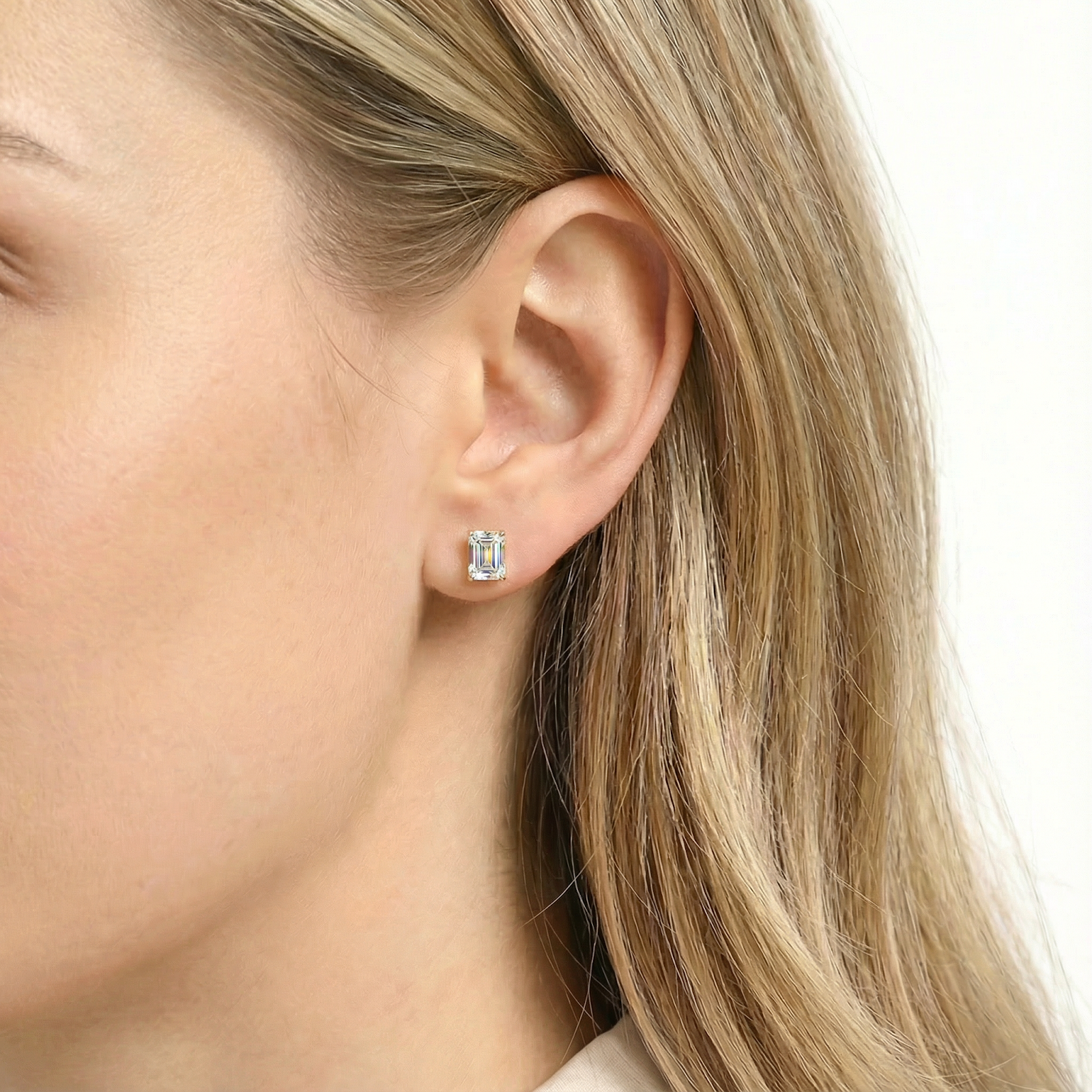 Baguette cut simulated diamond stud earring in 18K gold vermeil worn on a woman's ear.