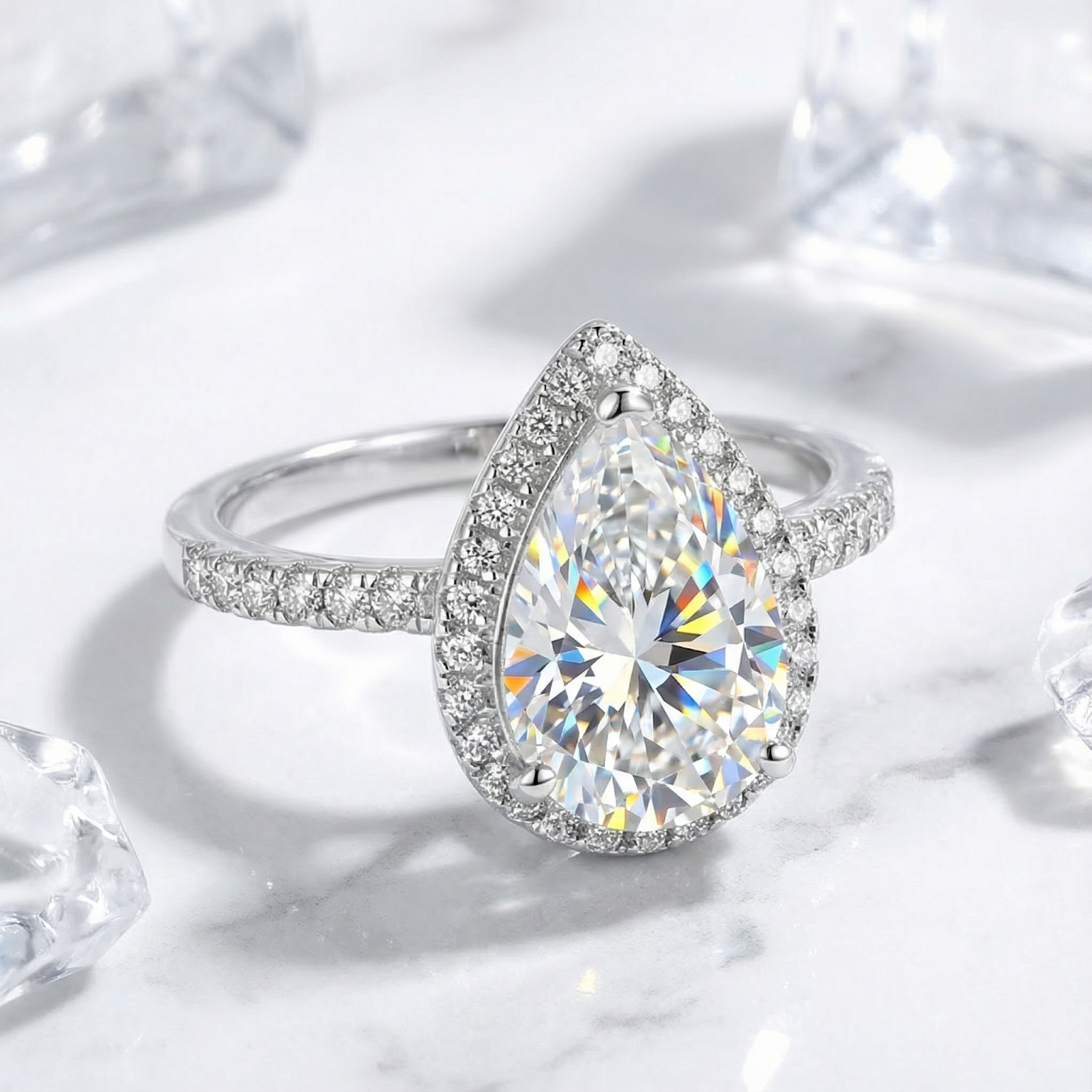 Angled side view of a pear-cut simulated diamond halo ring in S925 sterling silver on a marble background.