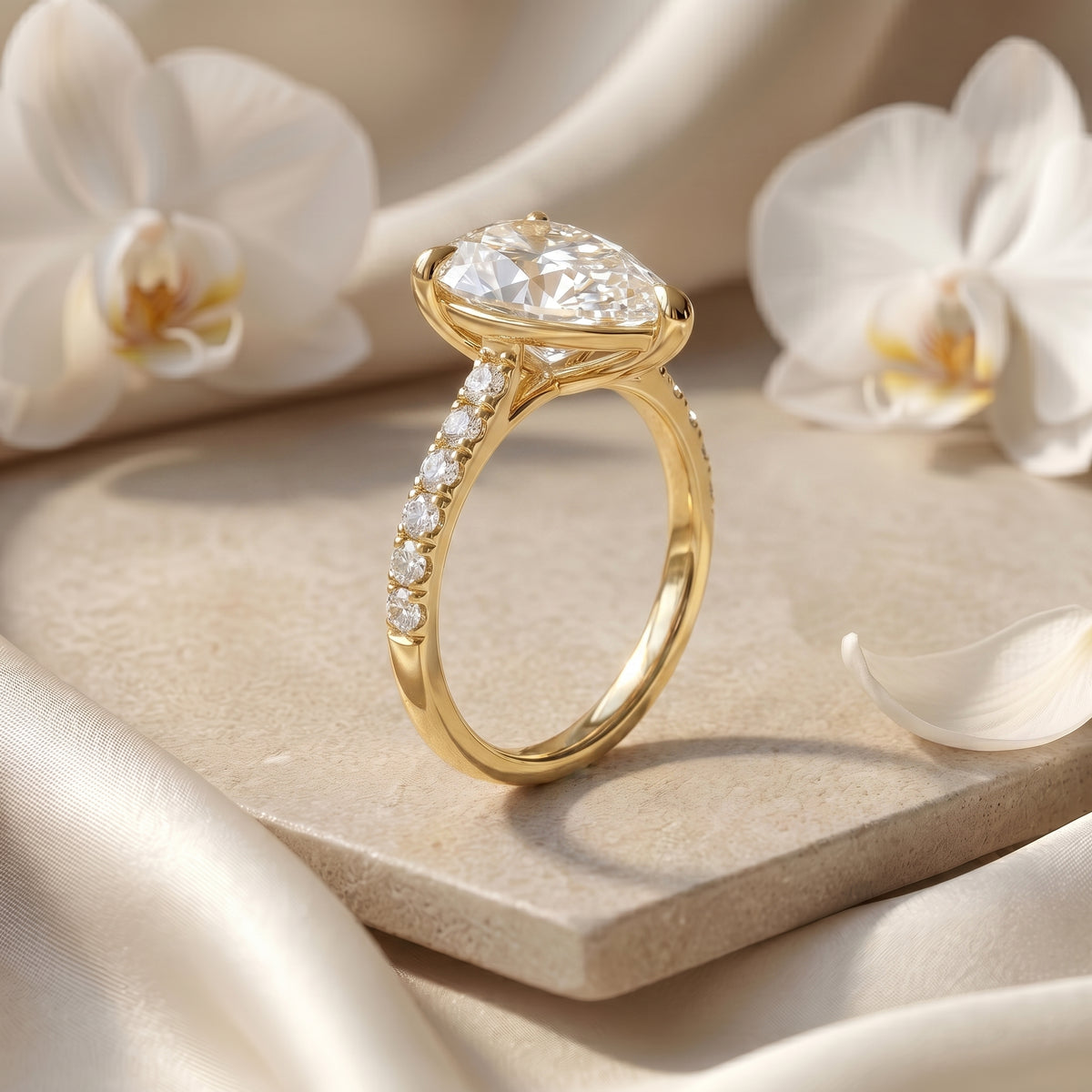 Close-up profile of a gold-tone pear-cut ring showing the raised setting and pavé stones along one side of the band.