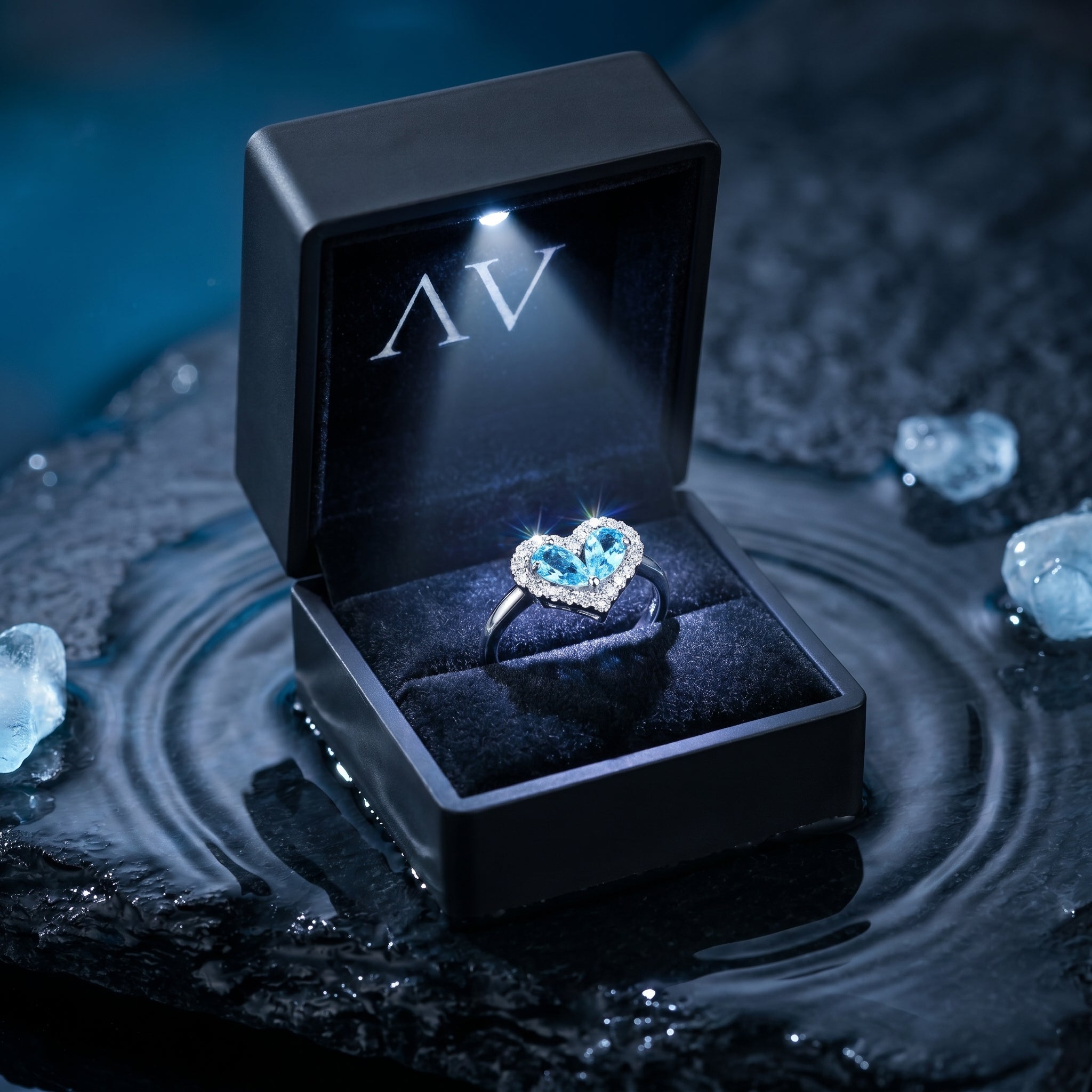Heart-shaped aquamarine halo ring presented in a lighted black jewelry gift box on a wet stone surface.