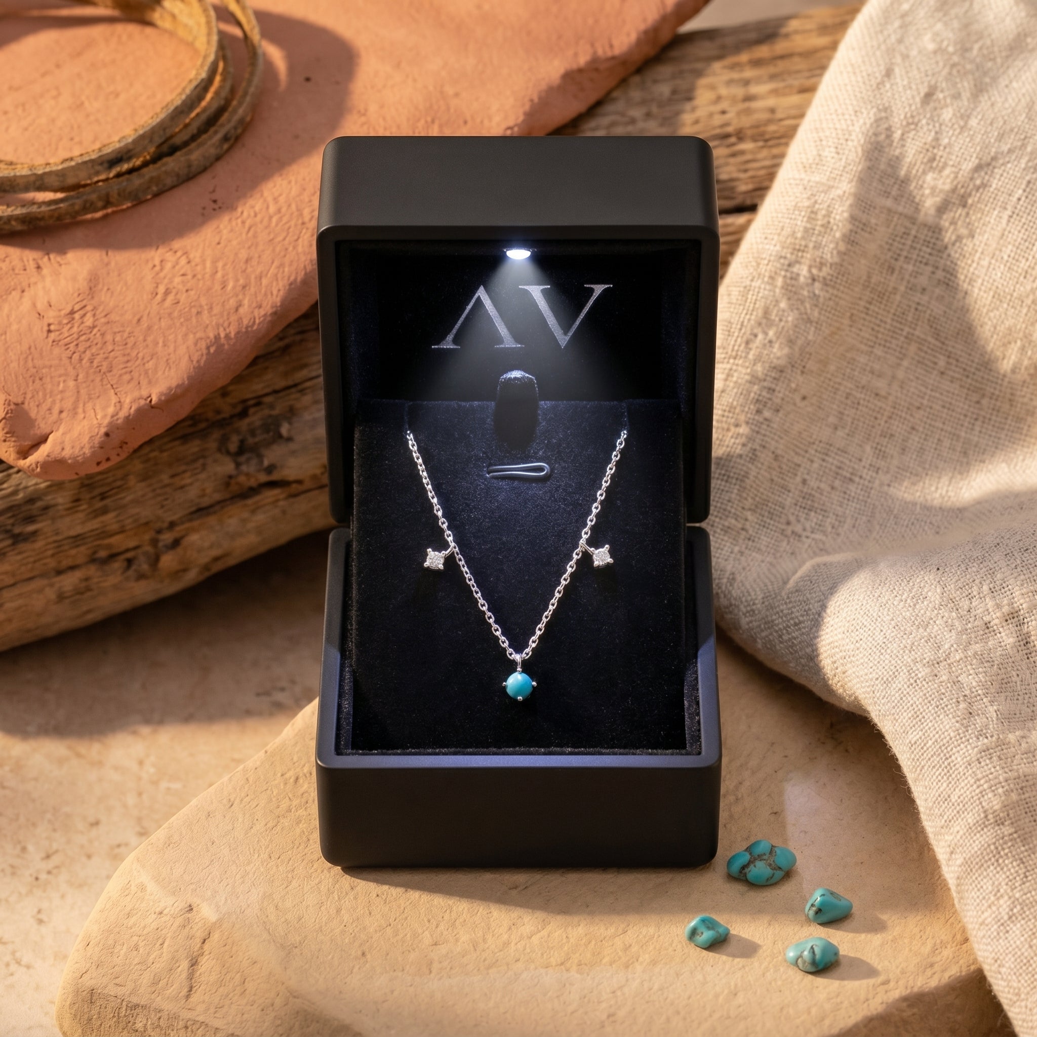 Silver turquoise necklace displayed in a premium black LED-lit jewelry gift box on a desert-themed background.