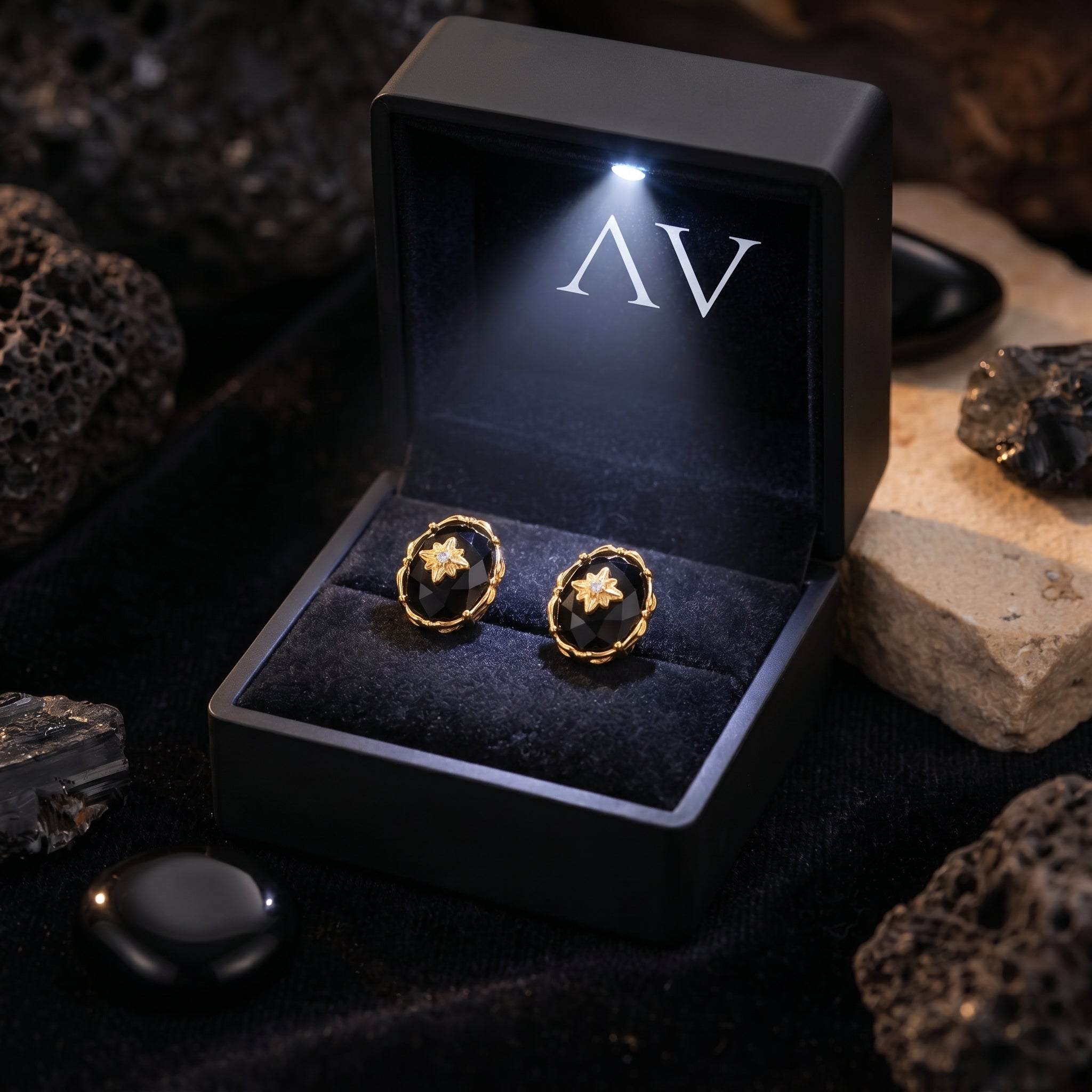 Yellow gold oval-cut faceted black onyx earrings in a black LED-lit jewelry box with AV logo.