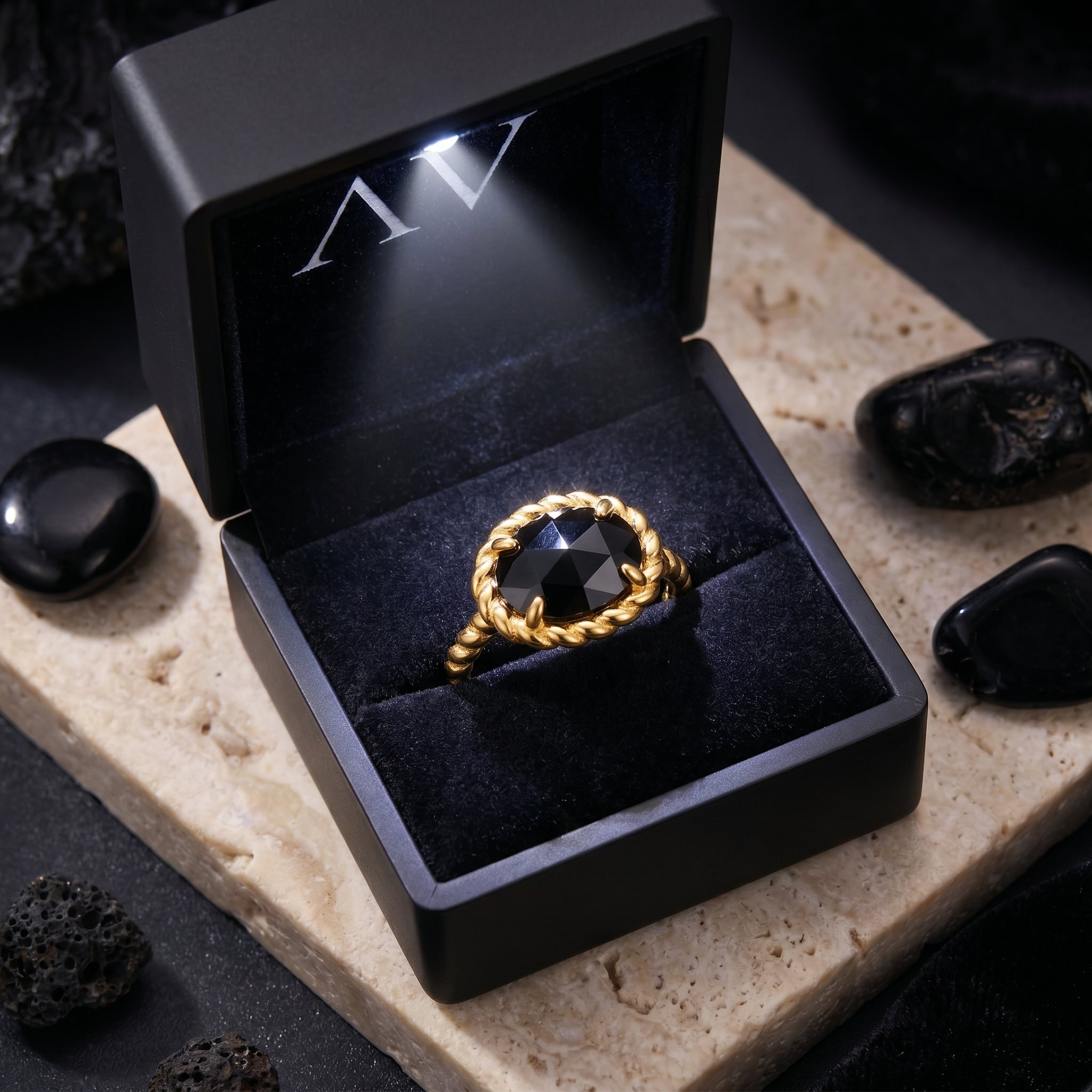 The Calisto black onyx ring presented in a premium black lighted jewelry gift box on a stone surface.