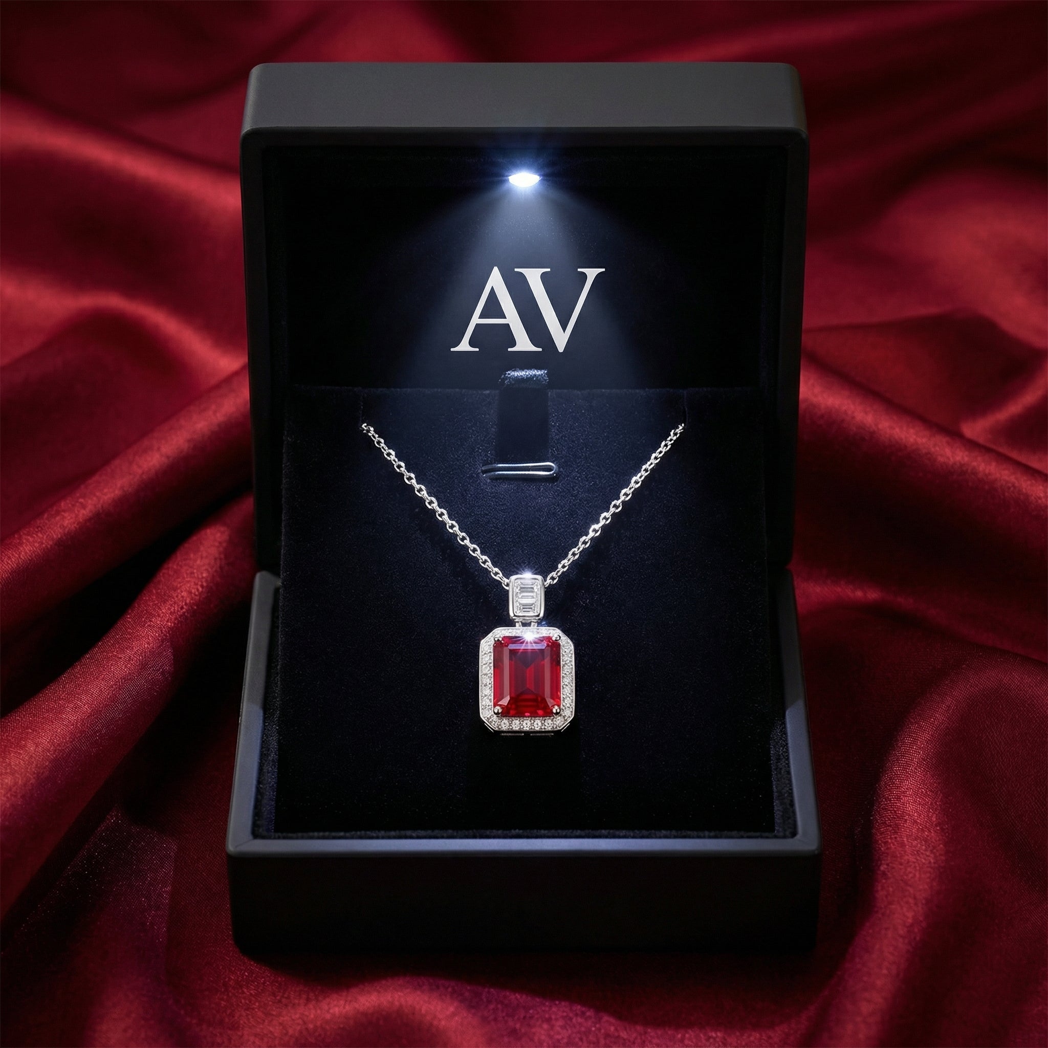 Emerald cut simulated ruby necklace inside a lighted black jewelry gift box on red satin.