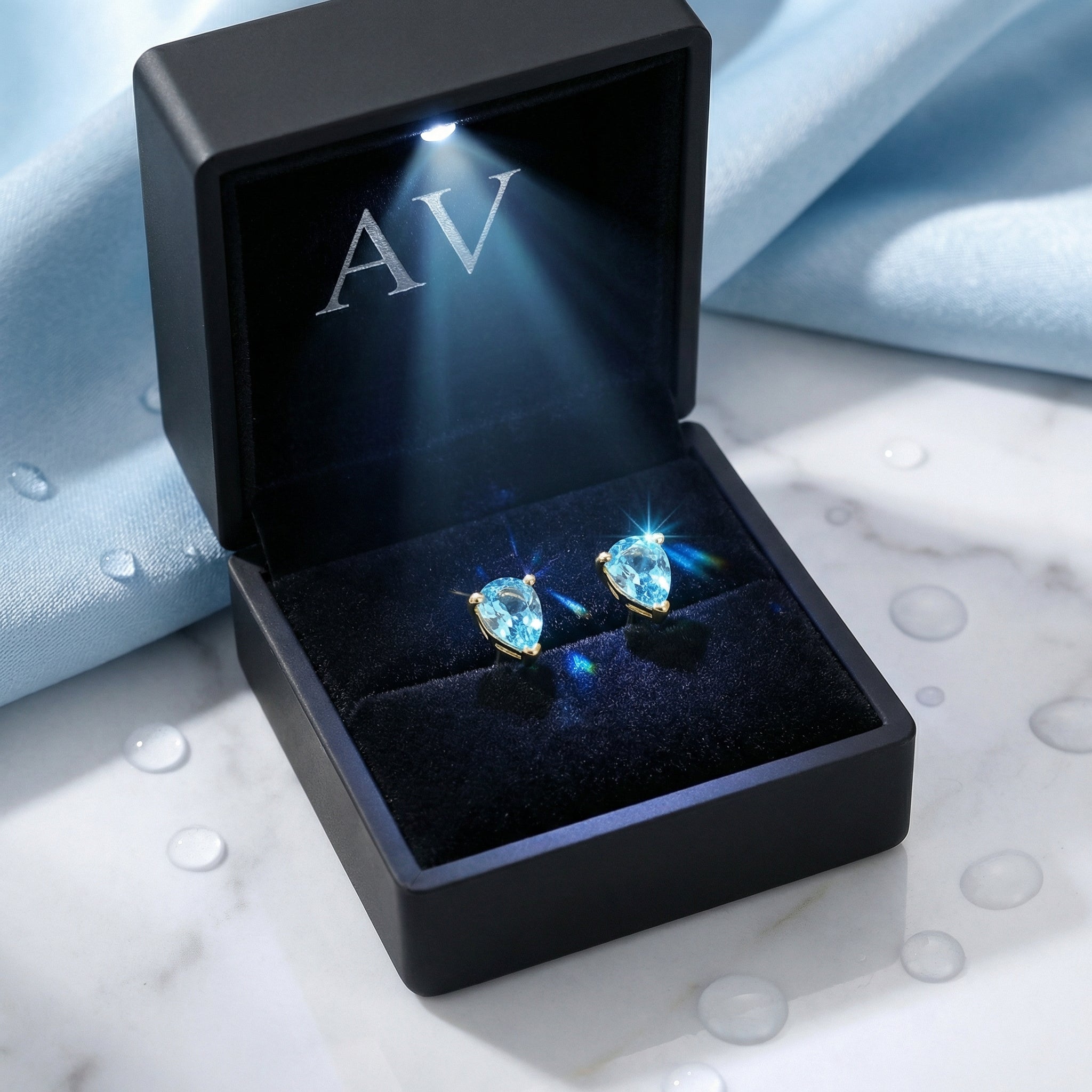 Pear cut simulated aquamarine teardrop earrings in a lighted black AV branded jewelry gift box.