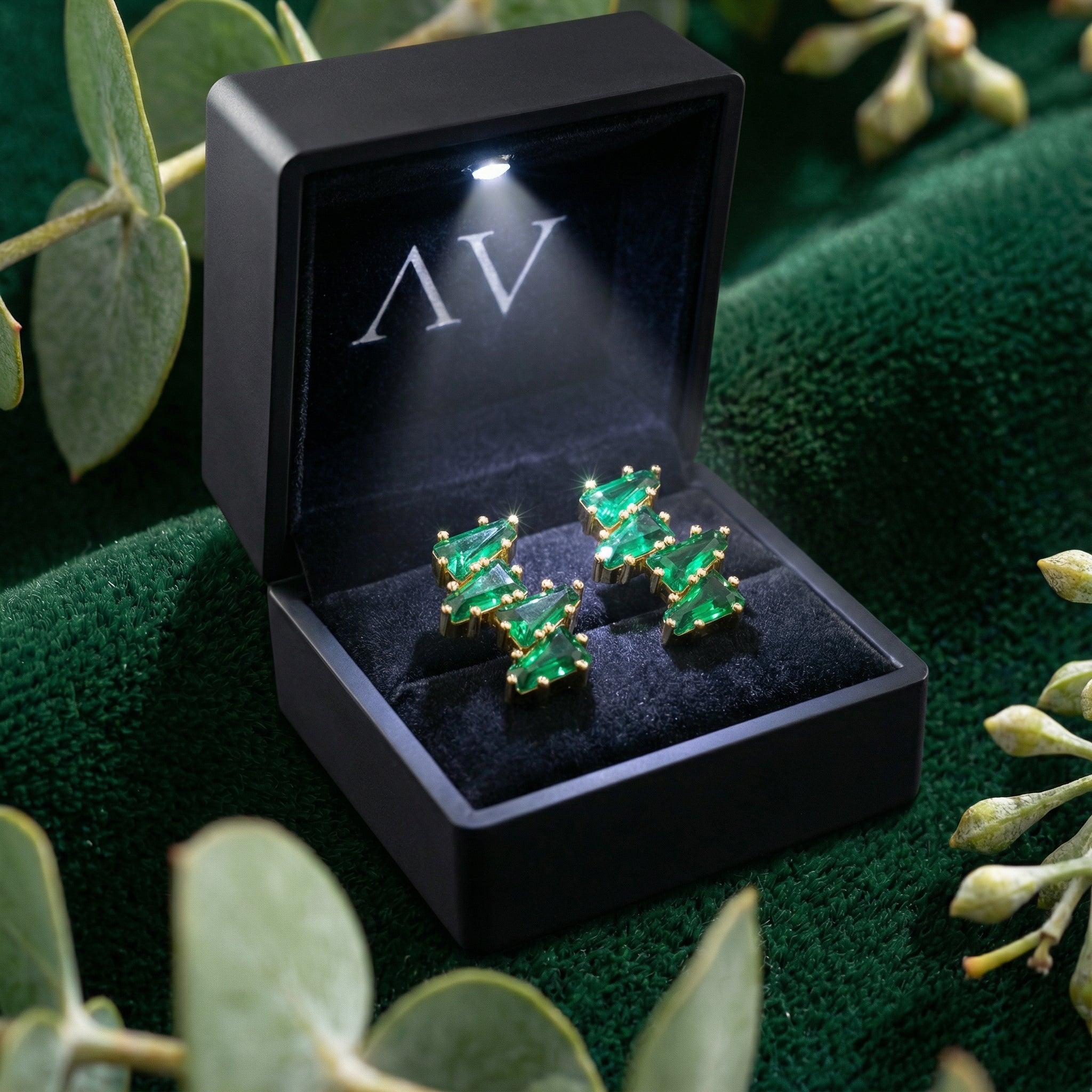 18K gold vermeil simulated emerald taper earrings inside a black lighted presentation box.