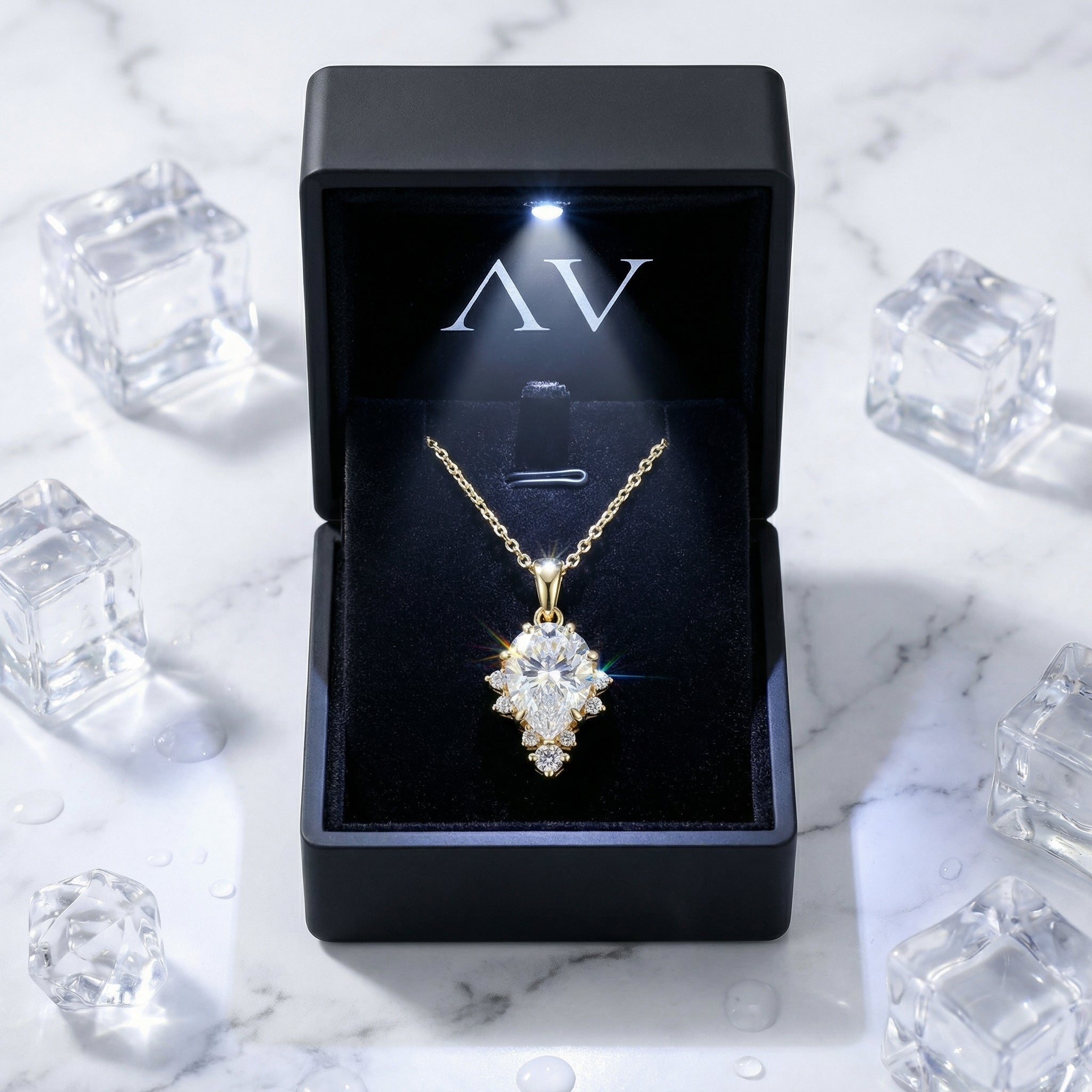 Pear-cut zirconia necklace in 18K gold vermeil inside a lighted black jewelry box on marble with ice.