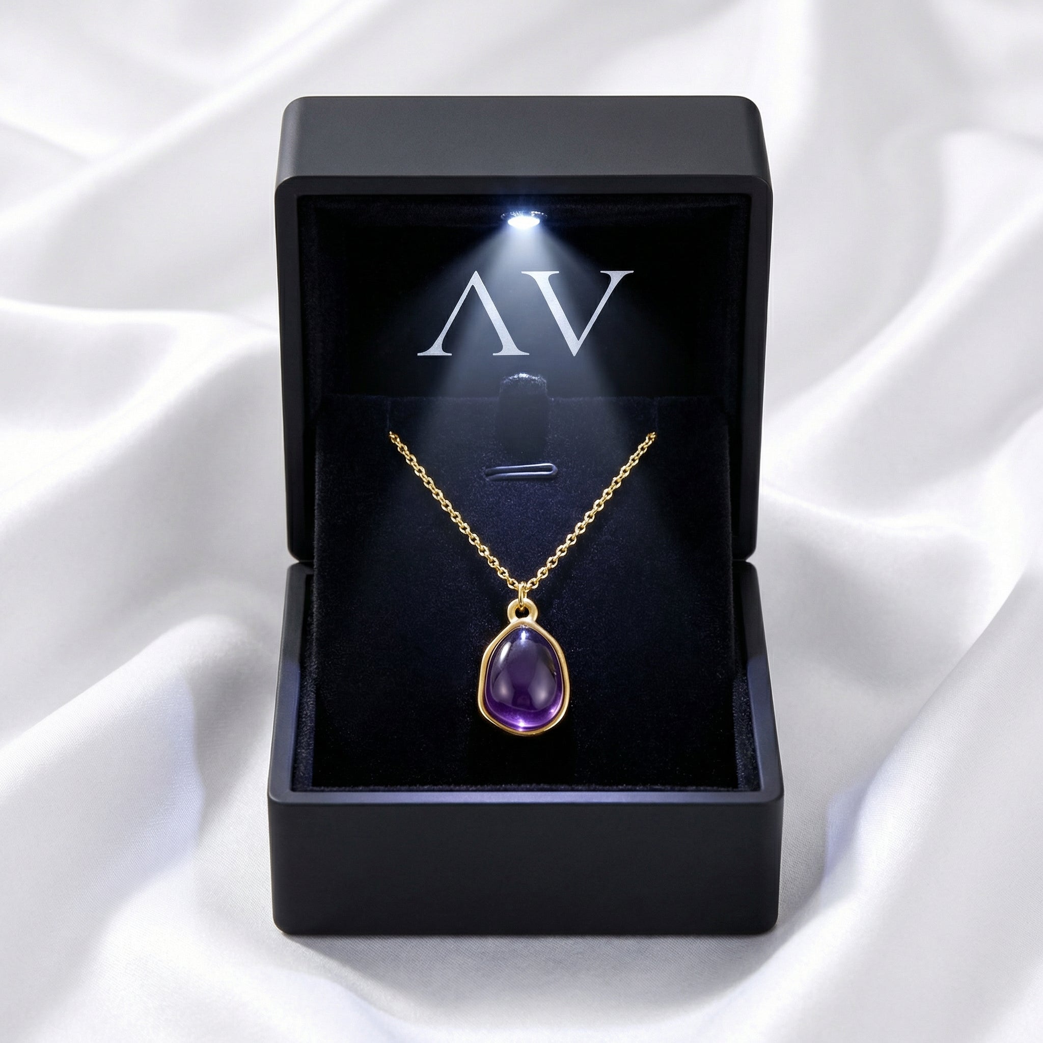 Yellow gold teardrop simulated amethyst necklace inside a black LED-lighted jewelry presentation box.