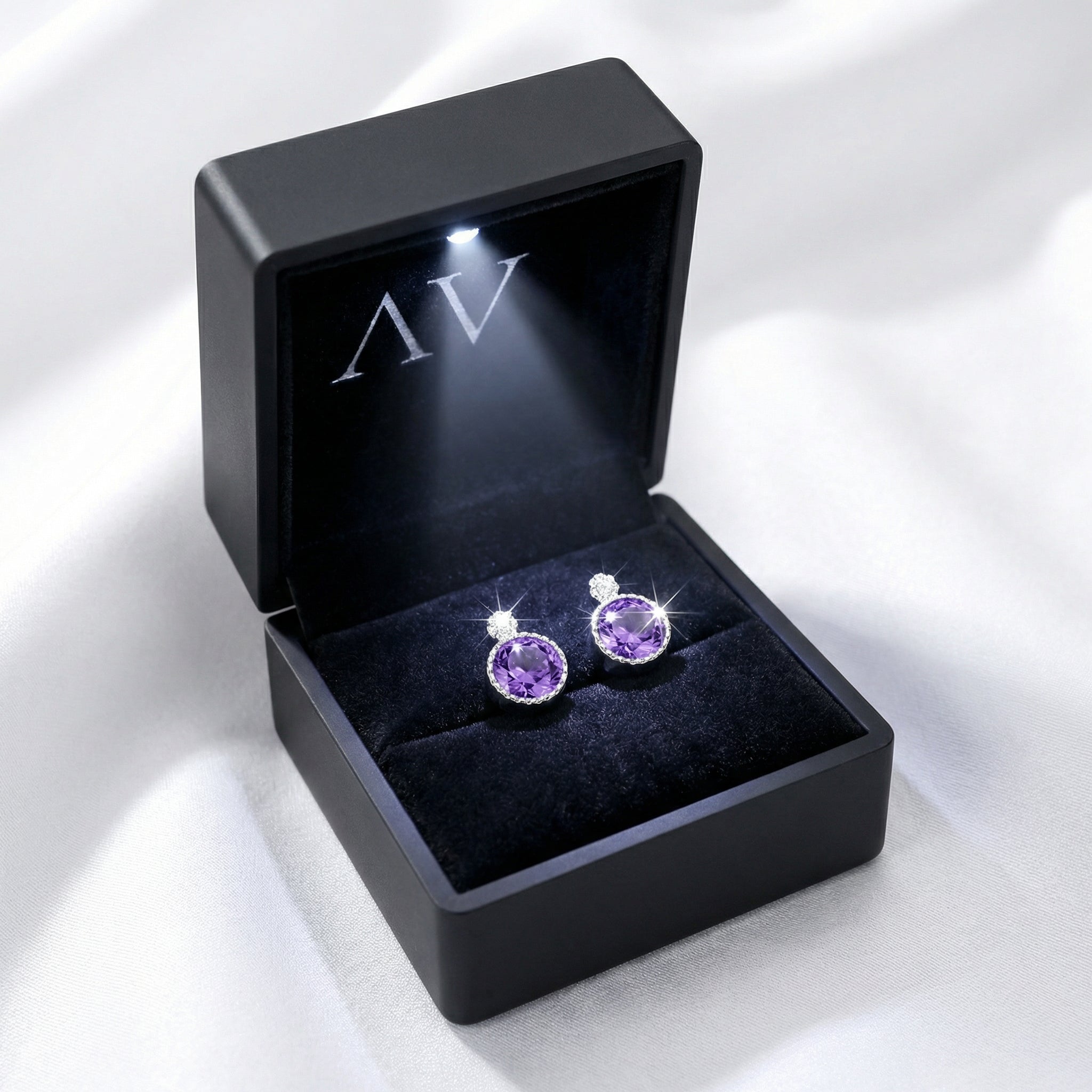 Round purple simulated amethyst stud earrings displayed inside a black LED-lit jewelry presentation box.