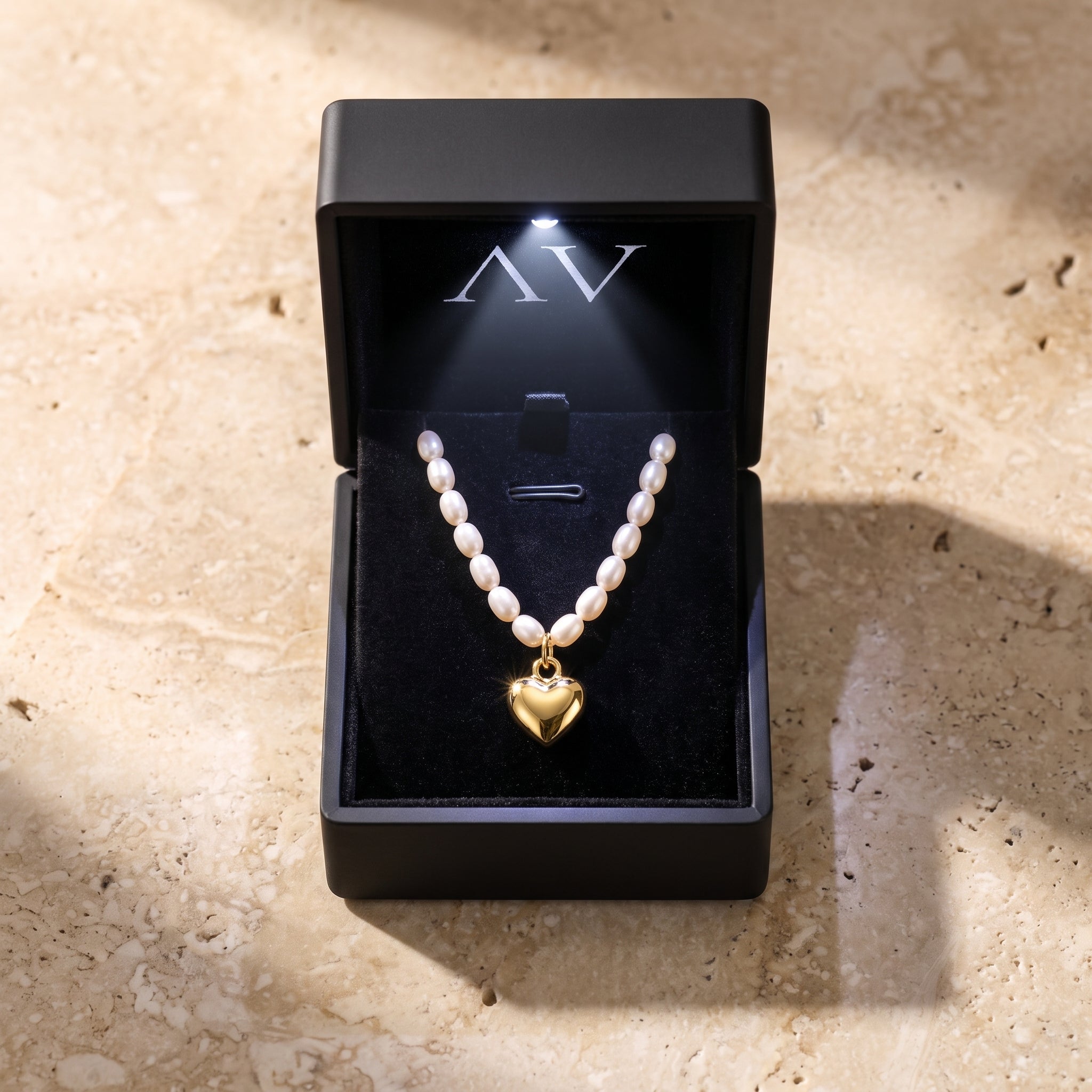 18K gold plated heart and white oval pearl necklace presented in a black lighted jewelry gift box.