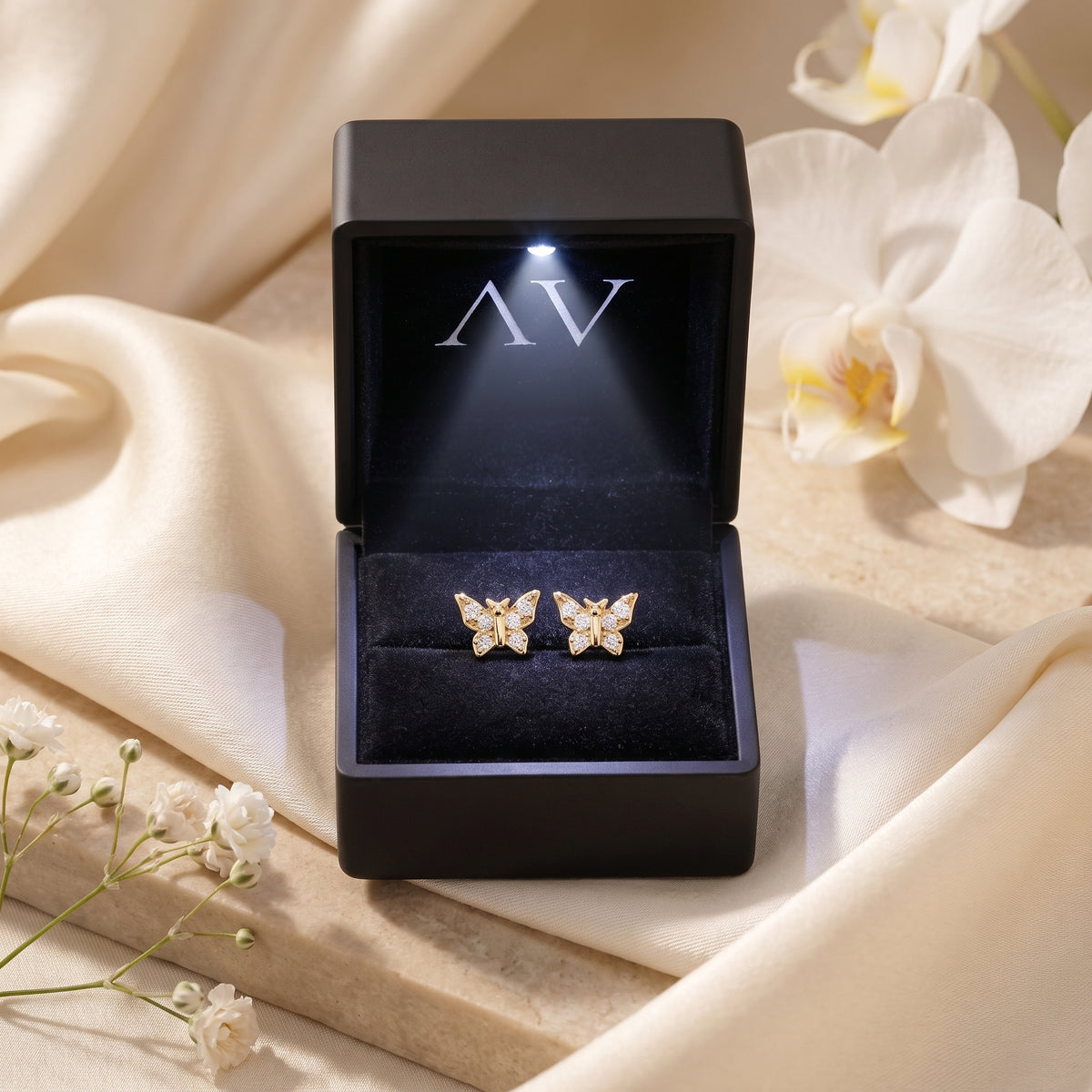 Gold butterfly earrings in lighted black gift box.