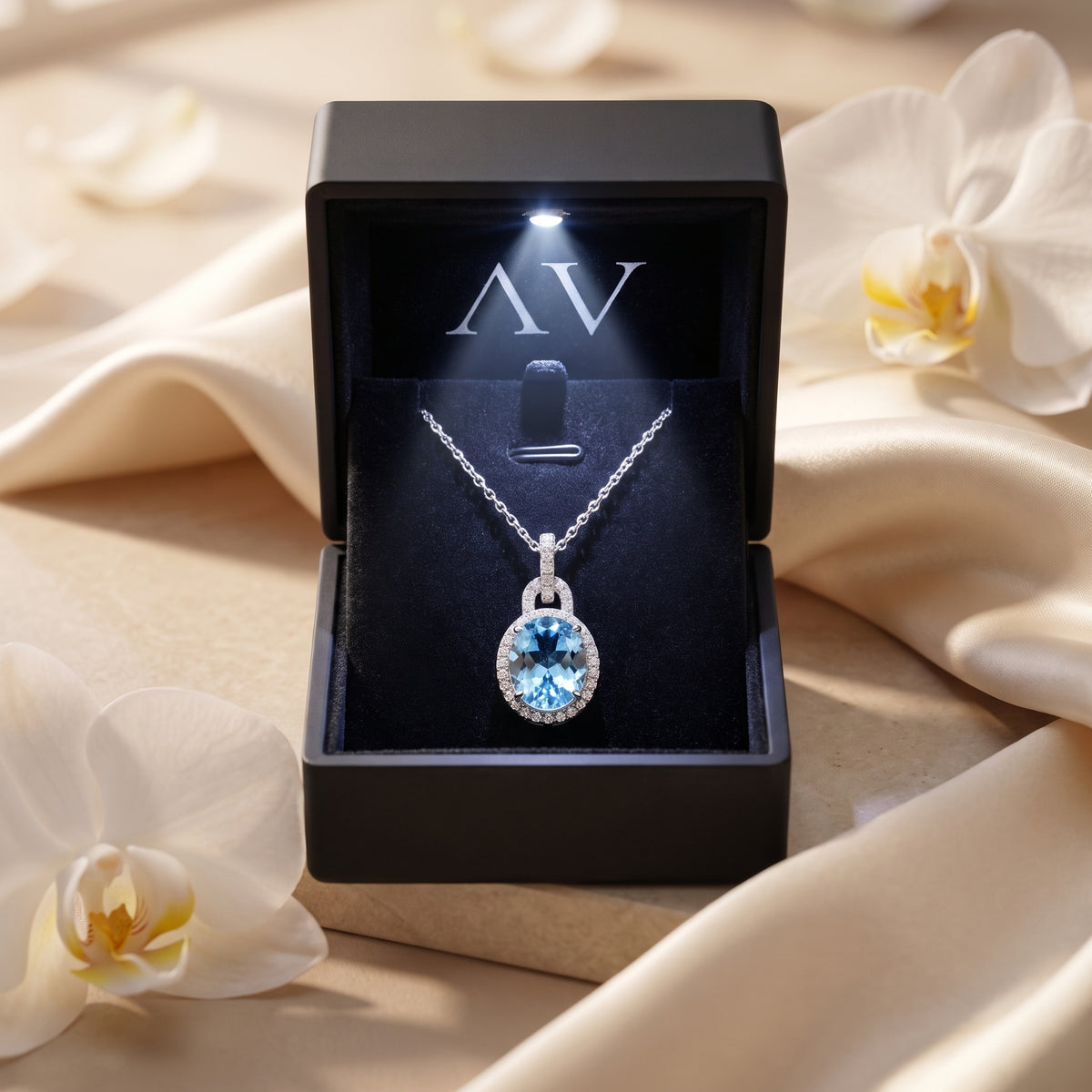 Bianca aquamarine pendant necklace inside a lighted black gift box with orchids.