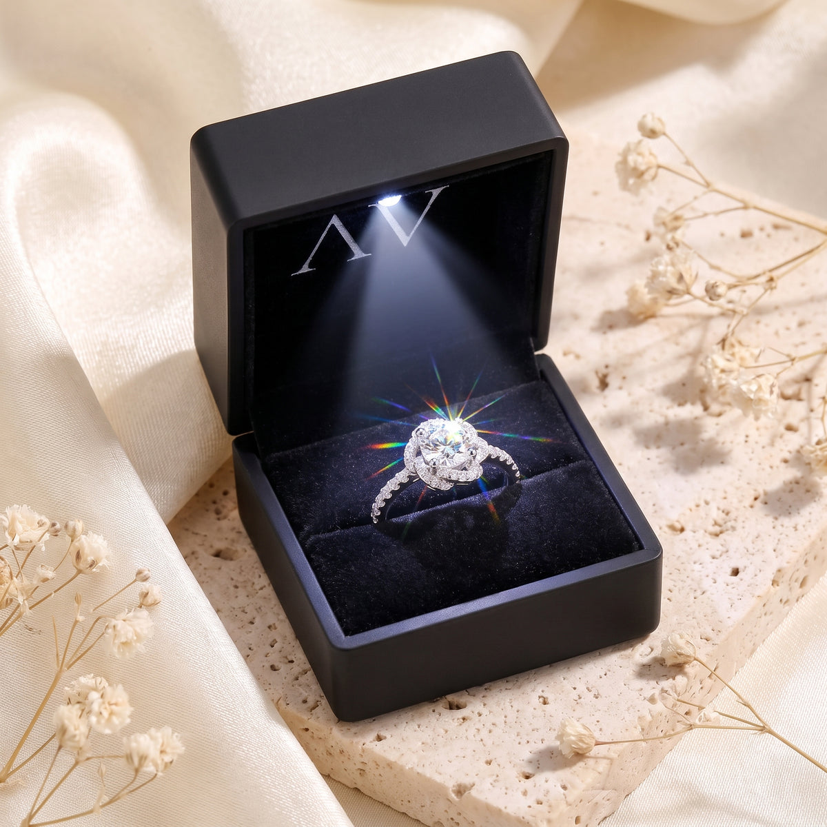 Silver rosette swirl halo ring with round simulated diamond in a lighted black velvet presentation box.