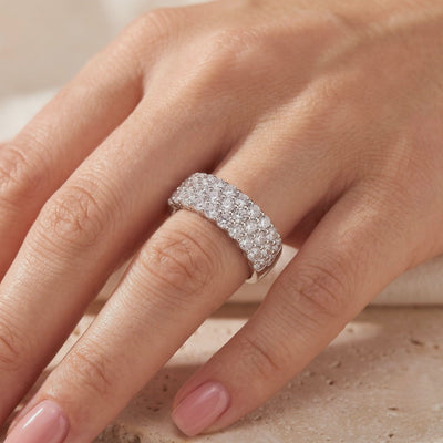 Wide silver multi-row pavé ring with sparkling round stones, worn on a hand.