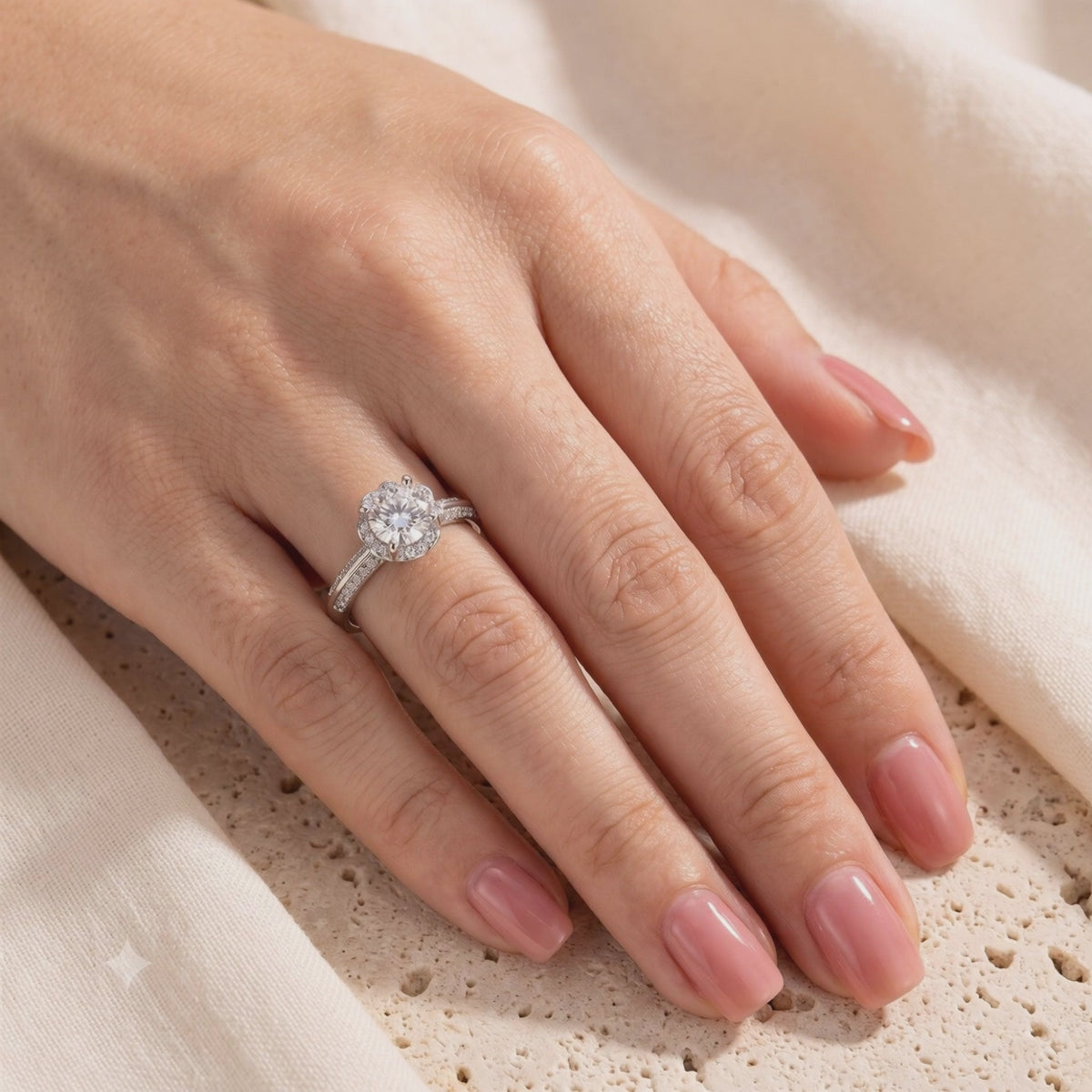 The Fleur Bloom Ring worn on a hand, showing its round center stone, flower-like halo, and pavé band.