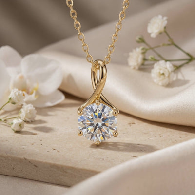 Gold-toned Lylianne necklace with a twisted loop pendant and round clear stone displayed among white flowers.