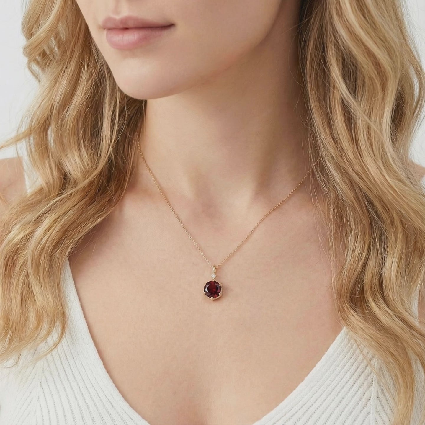 A solid gold necklace with a simulated garnet pendant.