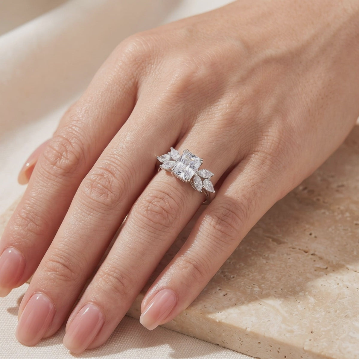 Close-up video of the silver ring with a radiant-cut clear center stone and marquise accents worn on a hand.
