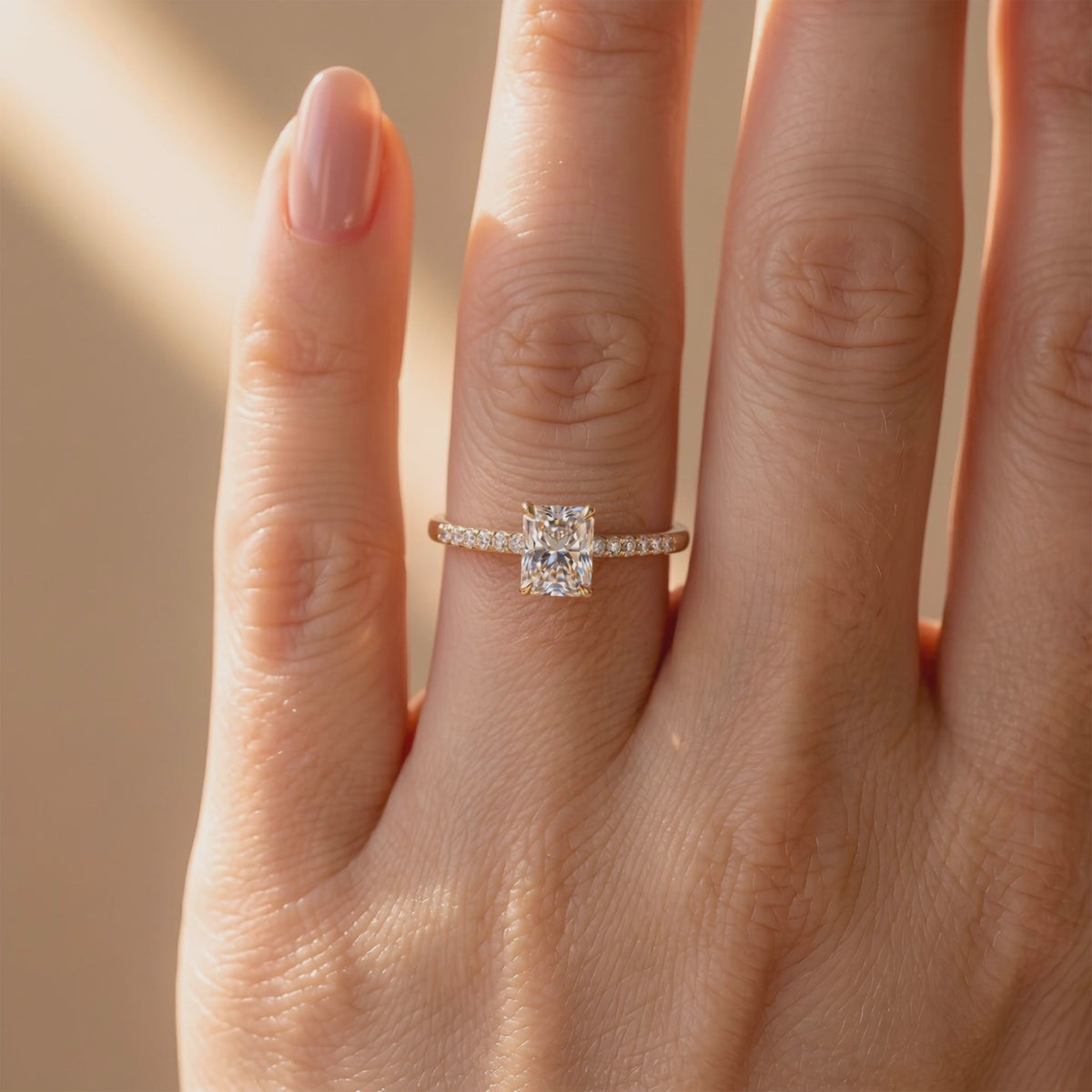Yellow-gold-tone pavé solitaire ring with a radiant-cut center stone worn on a finger