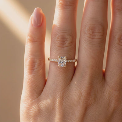 Yellow-gold-tone pavé solitaire ring with a radiant-cut center stone worn on a finger
