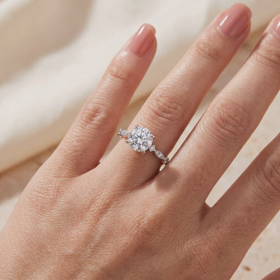 Round simulated diamond solitaire ring with a side-accented silver band, worn on a hand.