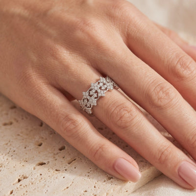 Silver snowflake-pattern ring with clear stones worn on a finger in close-up view.