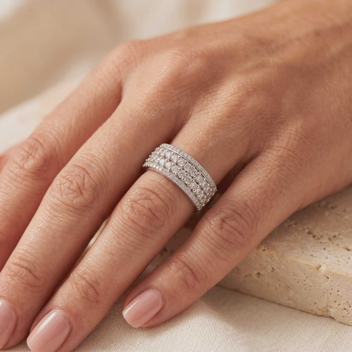 Wide silver multi-row cubic zirconia ring worn on a finger.