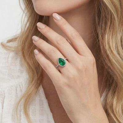 A solid gold ring with a pear-cut simulated emerald.