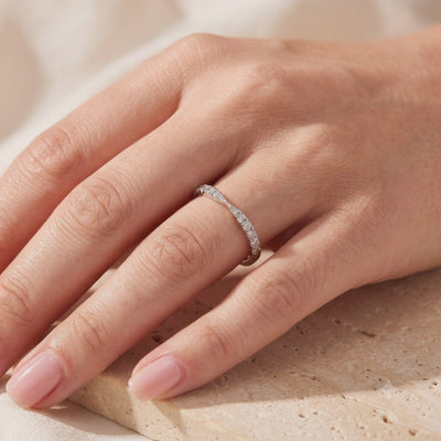 Silver contoured wave ring with small round stones worn on a finger.
