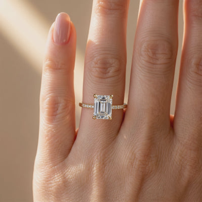 Emerald-cut pavé solitaire ring with a clear rectangular center stone, shown worn on a hand in a front view.