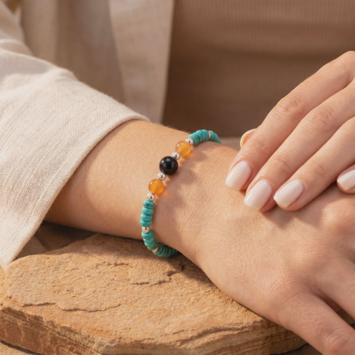 Turquoise, carnelian, and black onyx beaded silver bracelet worn on a model's wrist.