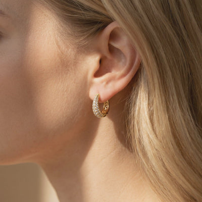 Model wearing a gold-tone J-hoop earring with multiple rows of round moissanite stones.