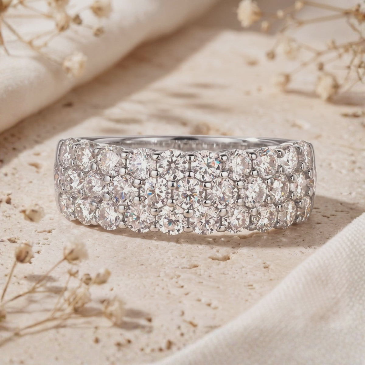 Close-up of a silver band ring featuring three rows of round pavé cubic zirconia.