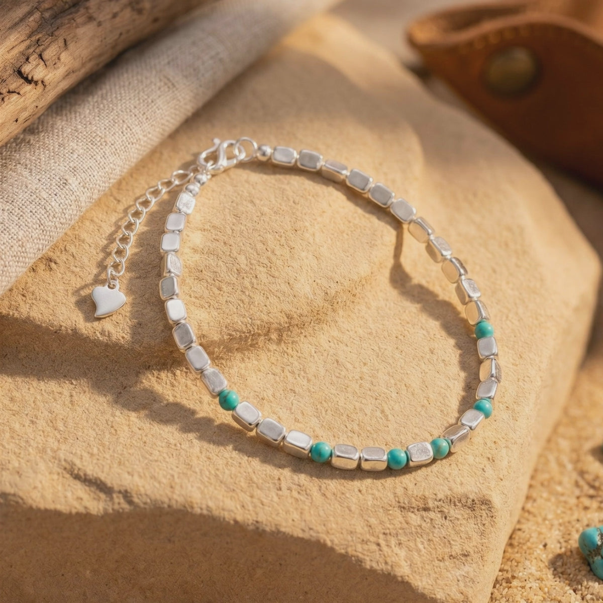 Alamosa turquoise and silver bead bracelet displayed on stone with its heart-shaped extender charm visible.