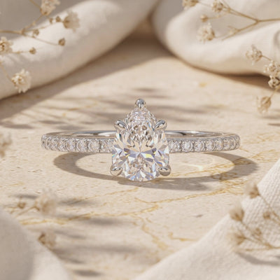 Close-up of a pear-shaped clear stone ring with a five-prong setting on a pavé band.