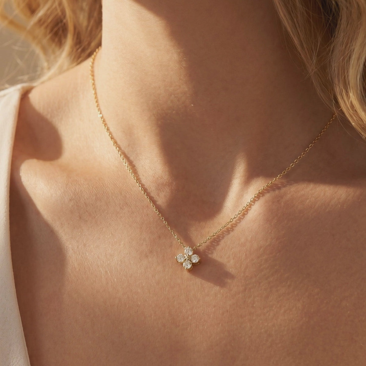 Woman wearing a gold-tone four-stone floral moissanite pendant necklace on her collarbone.