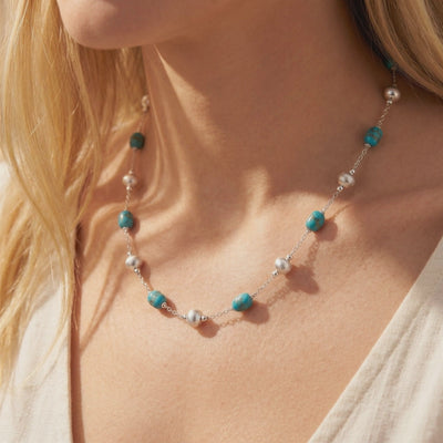 Pueblo turquoise necklace with alternating blue turquoise and round silver beads worn on a model’s collarbone.
