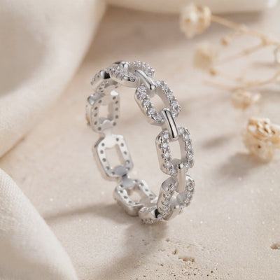 Close-up of a pavé chain-link ring standing on a light textured surface