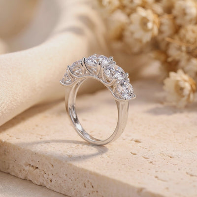 Side profile of a silver five-stone ring with graduated clear round stones on a textured stone slab