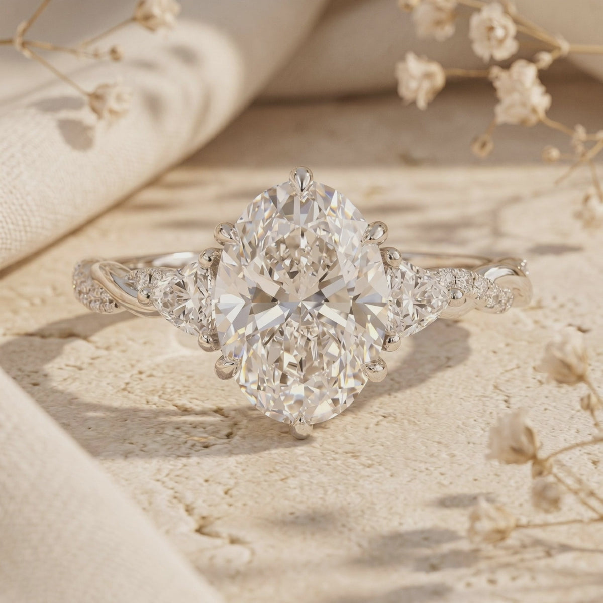 Studio shot of the silver Amalthea ring, featuring a large oval moissanite flanked by side stones on a twisted band.