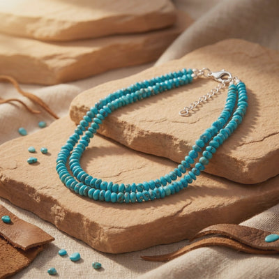 Double-strand turquoise bead necklace arranged on sandstone with its silver clasp and extender chain visible.