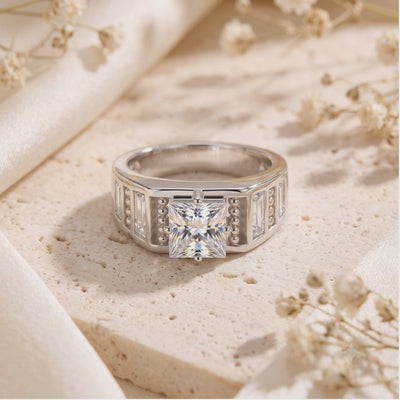 Front view of a silver ring with a princess-cut simulated diamond and baguette accents on beige stone.