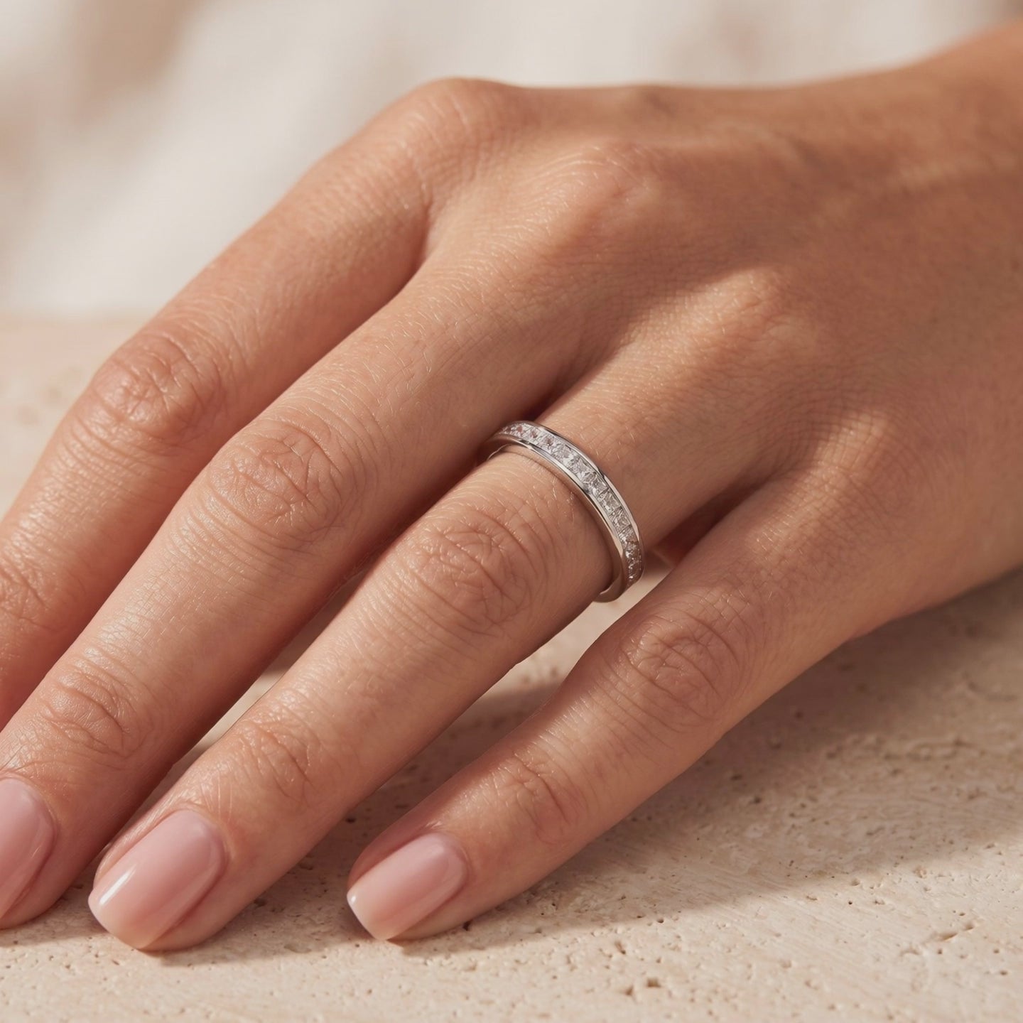 Silver channel-set eternity ring with princess-cut cubic zirconia worn on a hand