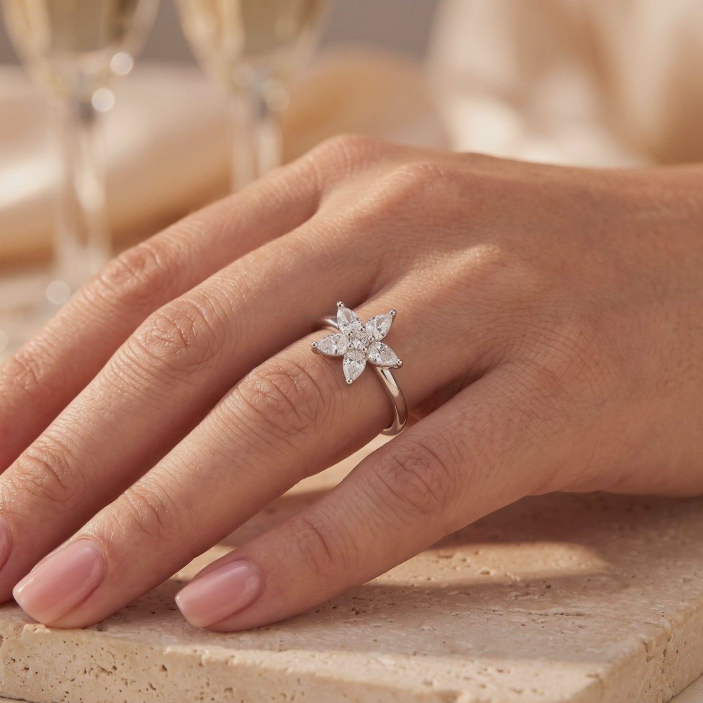 Silver ring with a five-petal pear-cut flower cluster, shown worn on a hand.