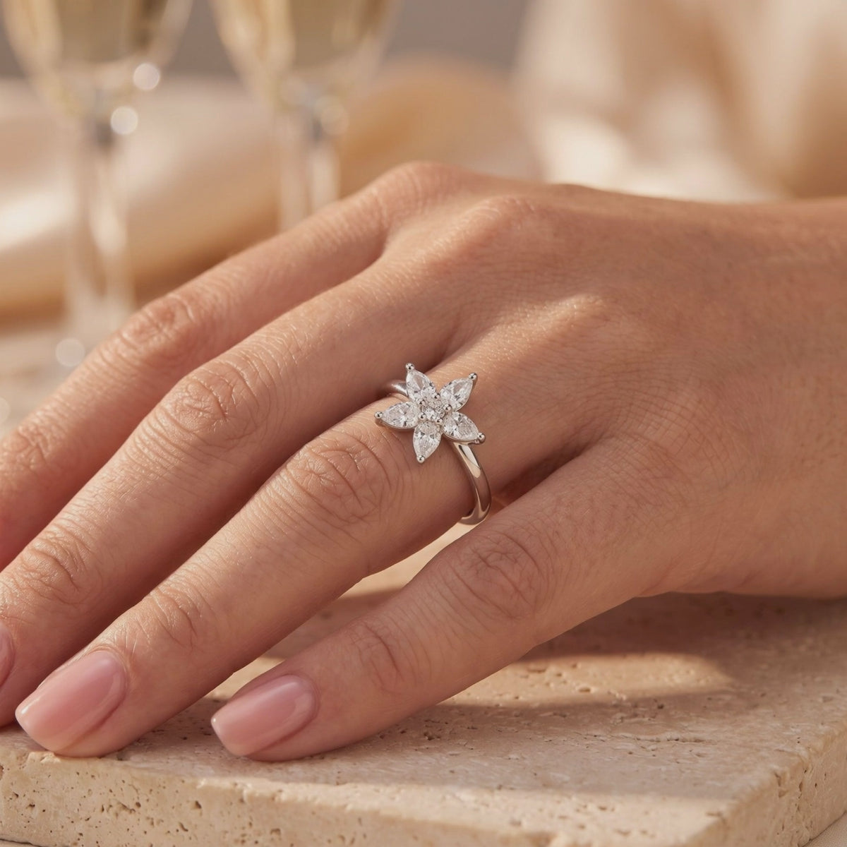 Silver ring with a five-petal pear-cut flower cluster, shown worn on a hand.