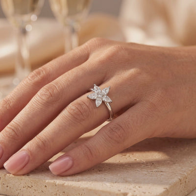 Silver ring with a five-petal pear-cut flower cluster, shown worn on a hand.