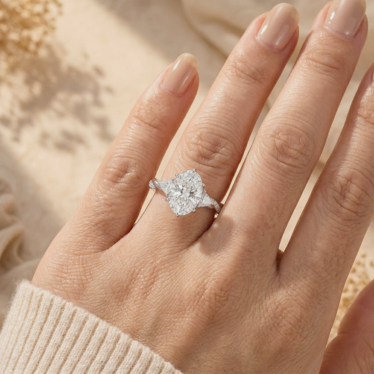 The silver Amalthea ring with an oval moissanite center stone worn on a finger, showing its twisted band.