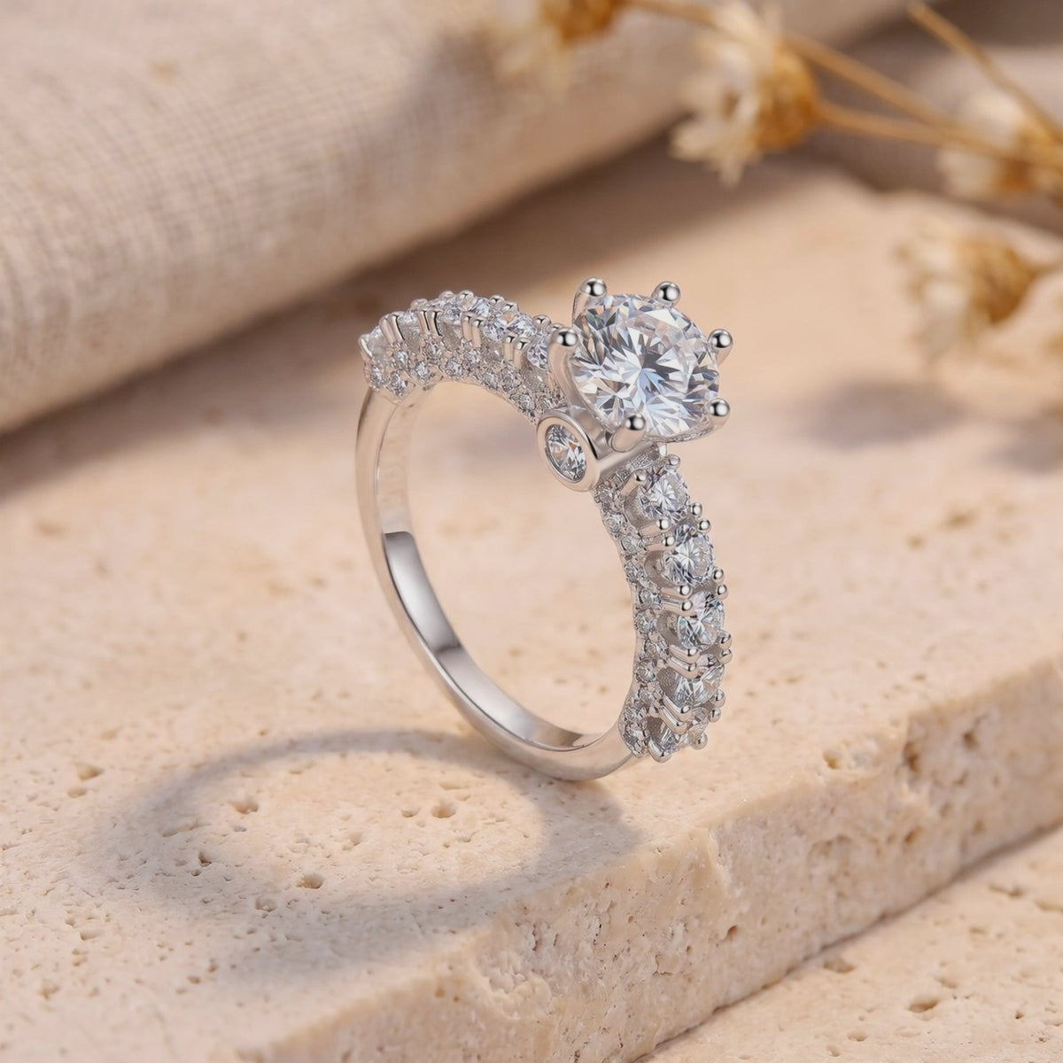 Close-up of the silver cathedral ring with a six-prong round center stone on a stone surface.