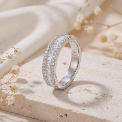 Silver baguette and micro-pavé cubic zirconia band standing upright on a textured beige stone block.