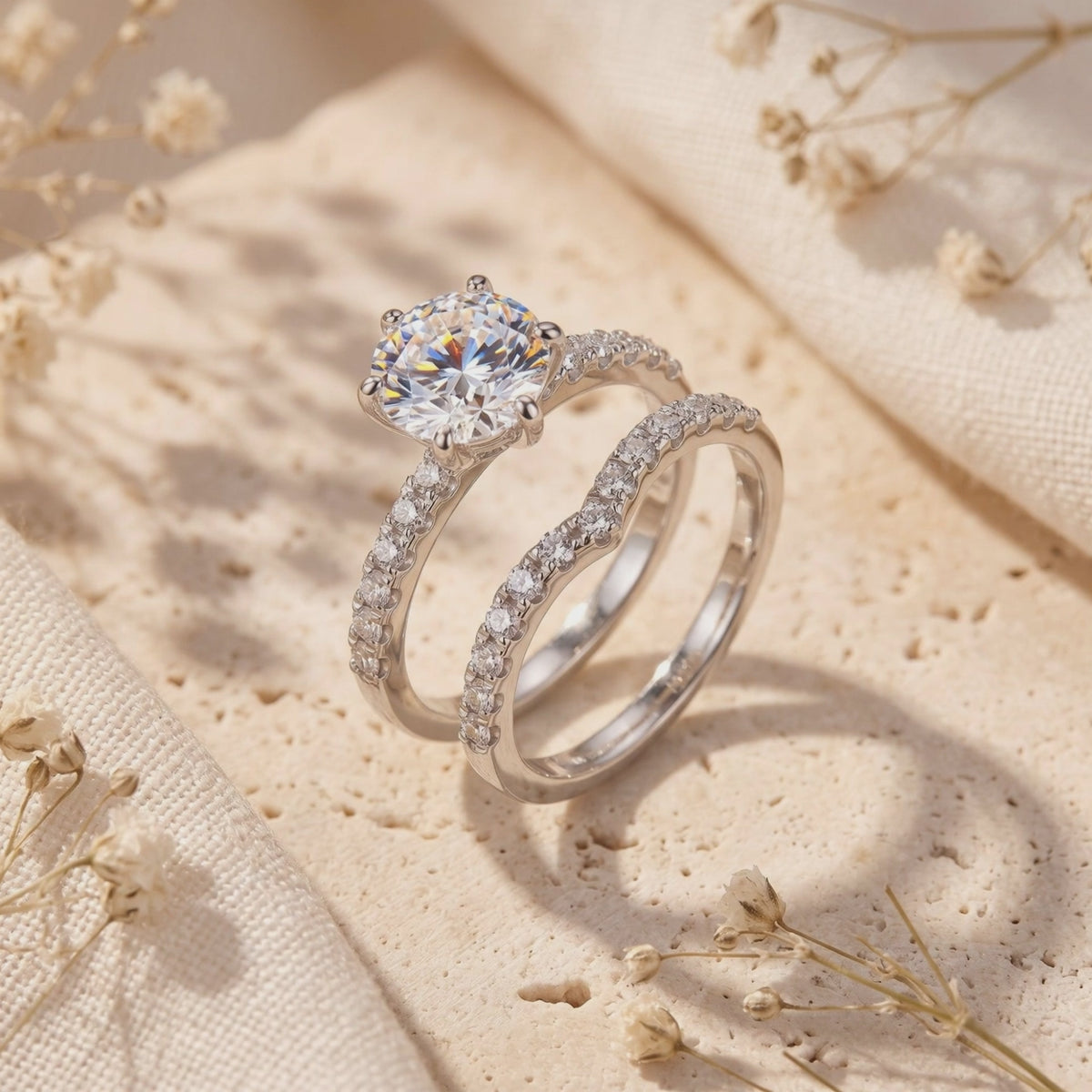 Sterling silver round solitaire ring and curved pavé nesting band displayed upright on a beige textured stone block.